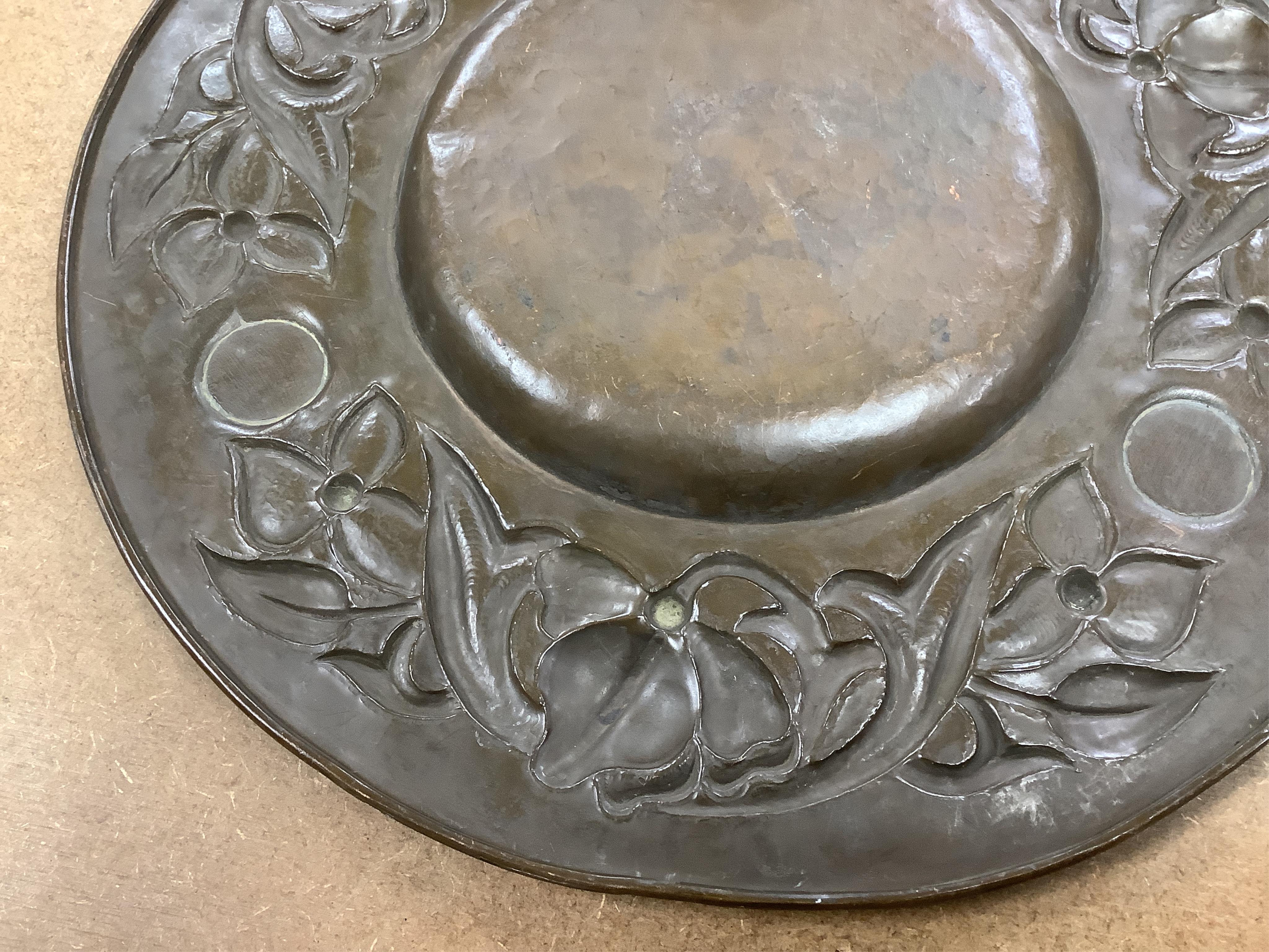 An Arts and Crafts embossed copper dish, in the manner of John Pearson, inlaid with Ruskin cabochons, unsigned, 32cm in diameter
